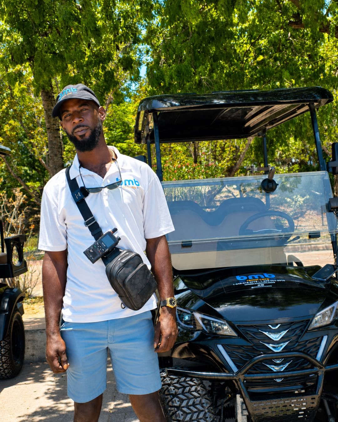 A BMB host in a marked polo stands next to a golf cart with the BMB logo on the hood.